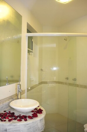 Une salle de bain avec une douche à parois de verre, un lavabo blanc et un miroir.