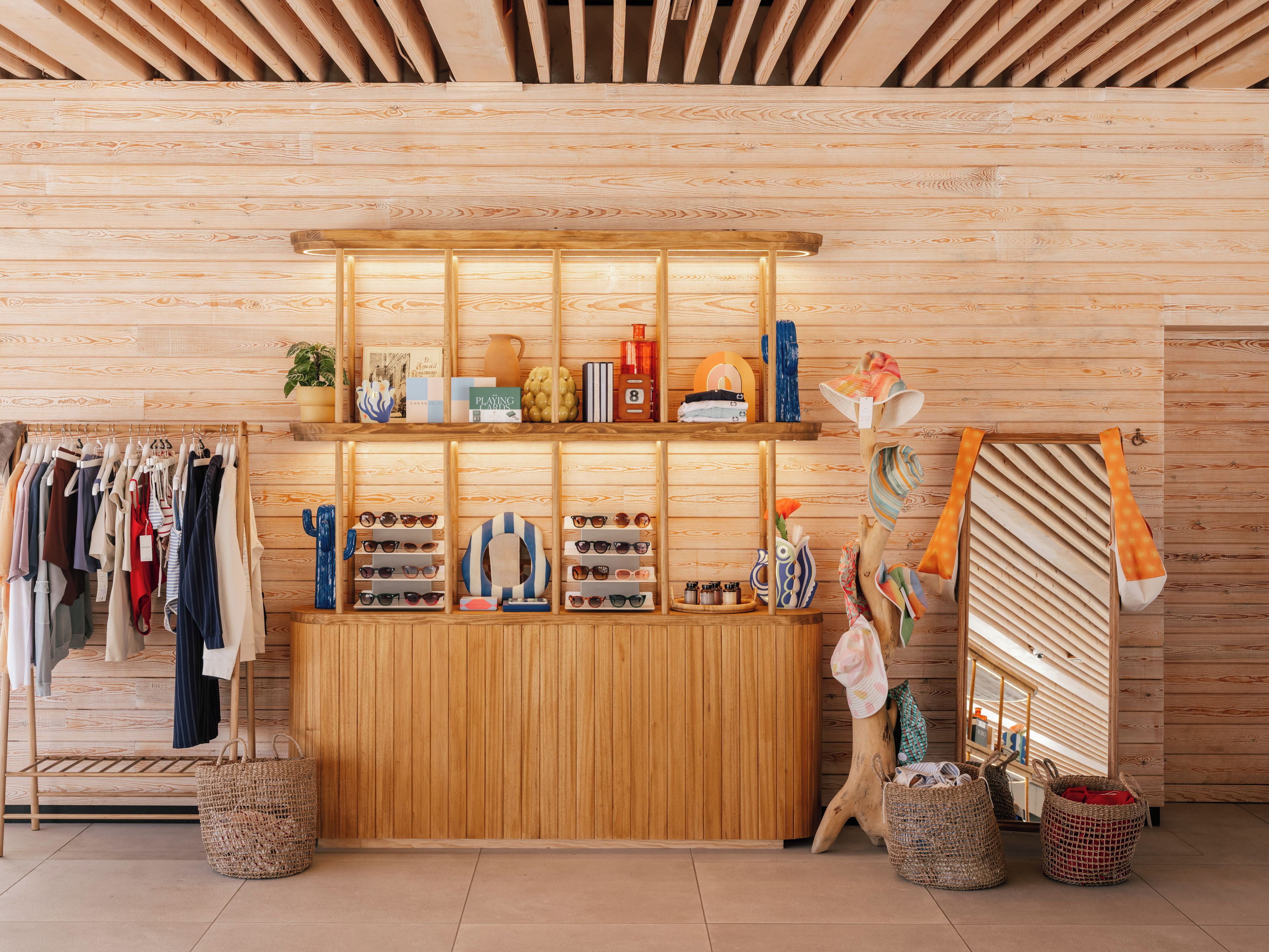 Una boutique con paredes de paneles de madera, percheros y estanterías con diversos artículos.