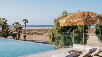 Una piscina al aire libre, sombrillas, sillones reclinables de piscina