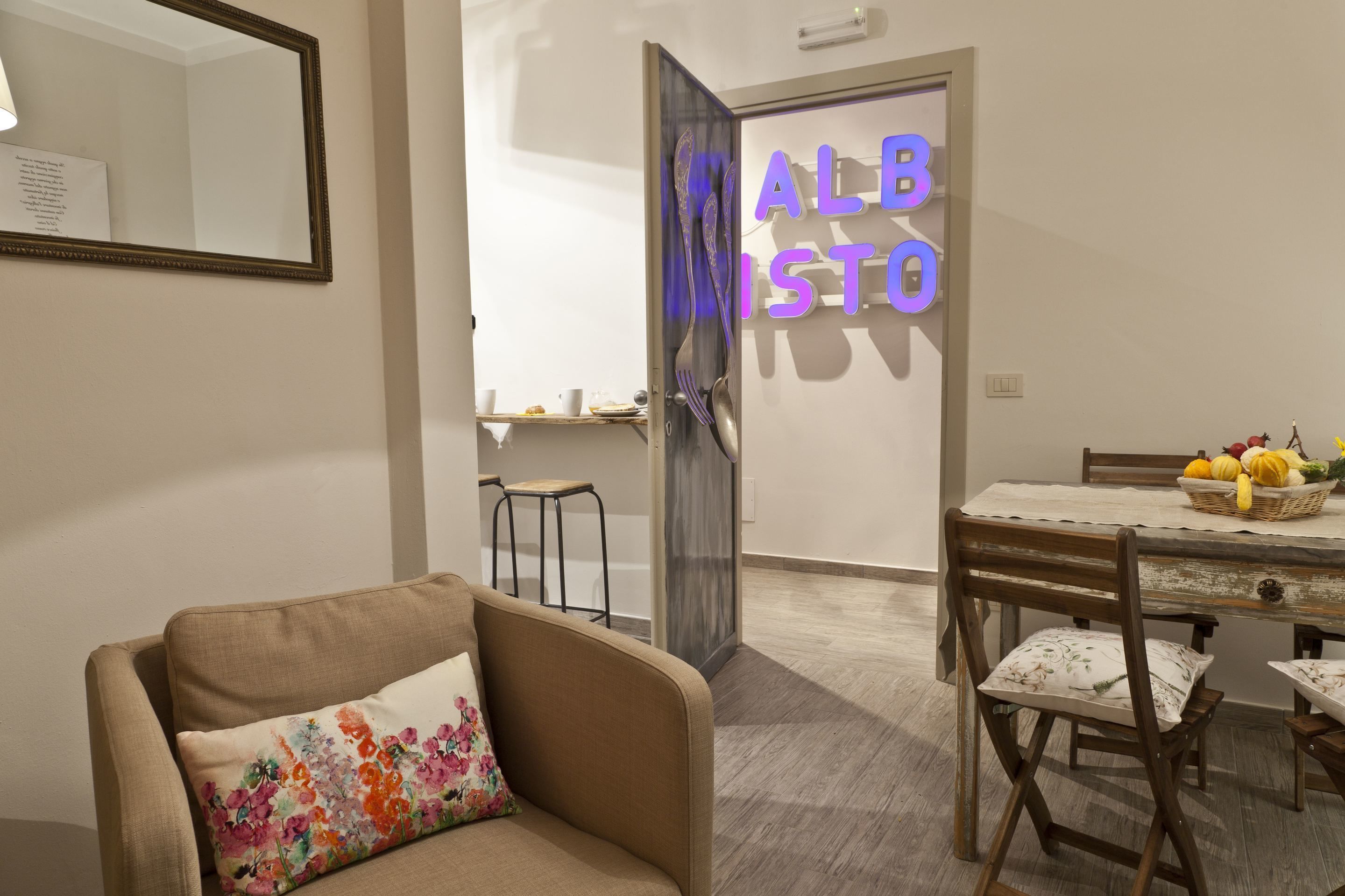 Una sala de estar con sofá, una mesa de comedor con sillas, y una cocina visible a través de una puerta abierta.