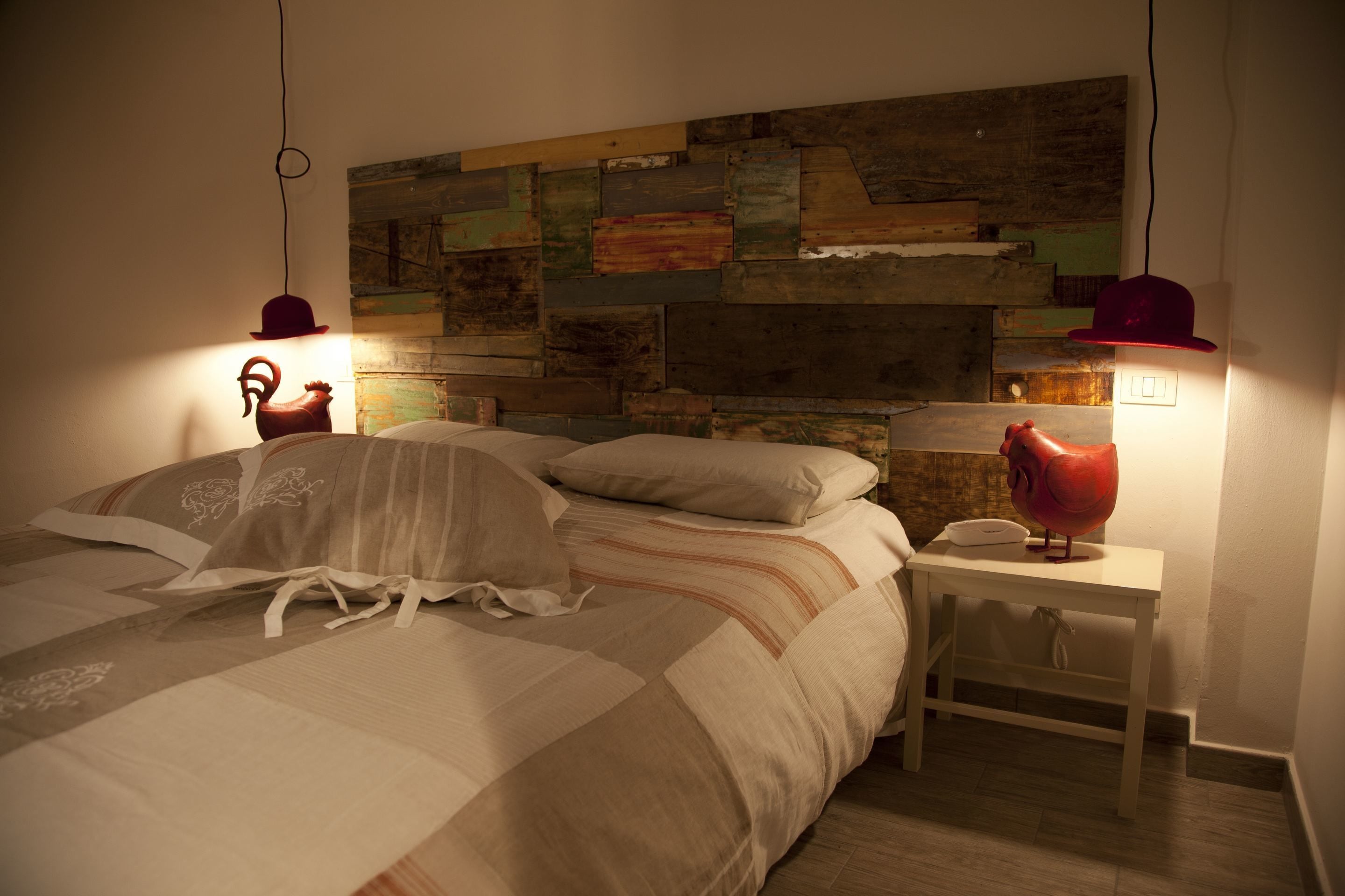 A bedroom with a wooden headboard, a bed with striped bedding, and two bedside tables with lamps.