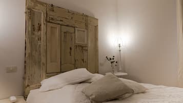 Une chambre à coucher avec un lit, une table de chevet, une lampe et un mur orné d’une porte ancienne.