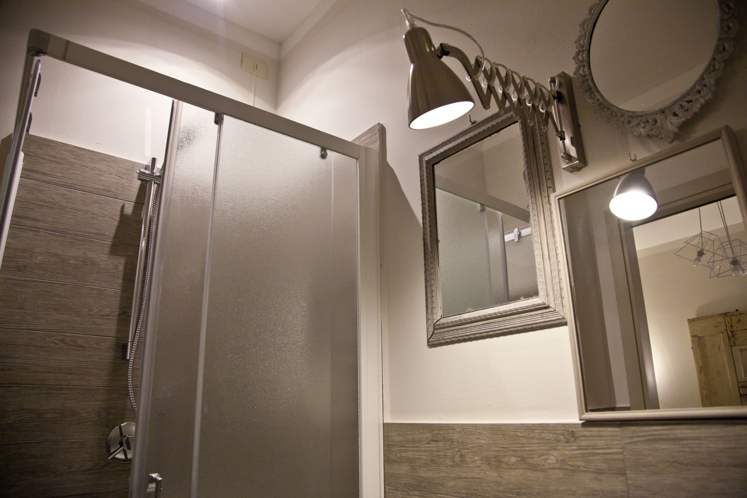 A bathroom with a shower, a mirror, and a light fixture.