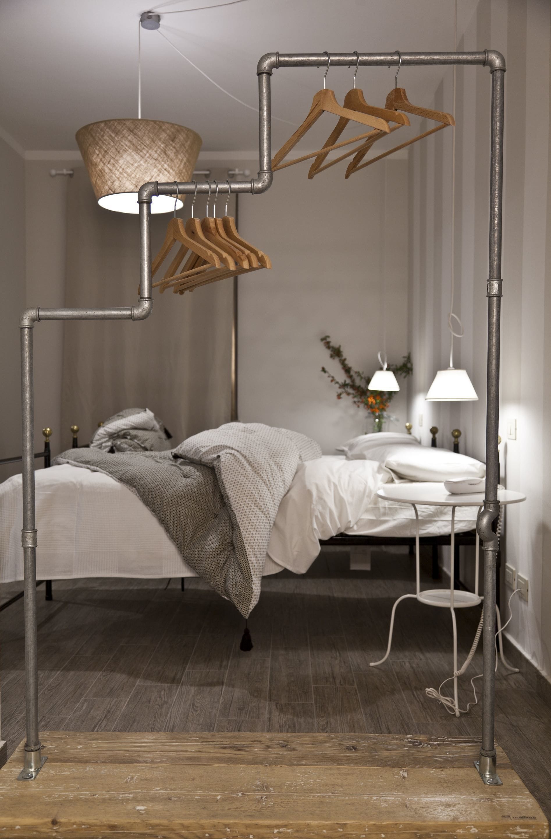 A modern bedroom with a metal frame bed, a hanging light fixture, and a bedside table with a lamp.