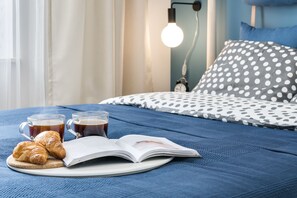 Ein ordentlich bezogenes Bett mit einem Kissen mit Punkten und einem Nachttisch mit Lampe.