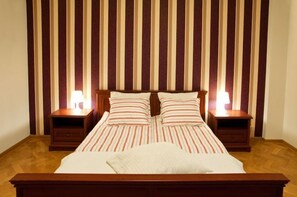 A neatly made bed with striped bedding and two bedside tables with lamps.