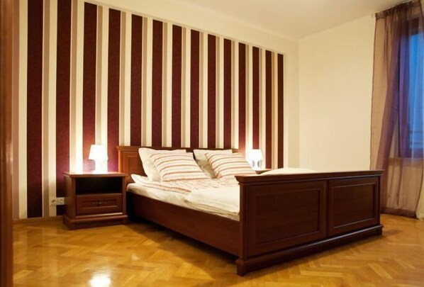 A bedroom with a wooden bed, a nightstand, and a striped wall.