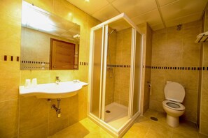 A bathroom with a shower, toilet, sink, and mirror.
