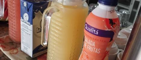 A kitchen counter with various food and drink items, including a carton of milk, a jar of sauce, and a bottle of fruit juice.