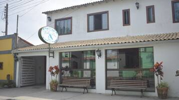 A building with a tiled roof, large windows, and a signboard.