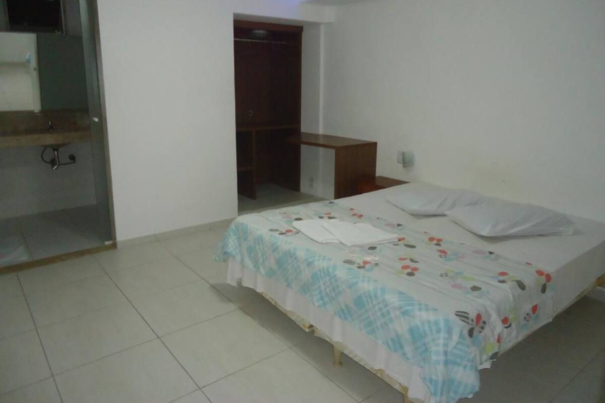 Un dormitorio con cama, mesita de noche, armario y cabina de ducha de vidrio.