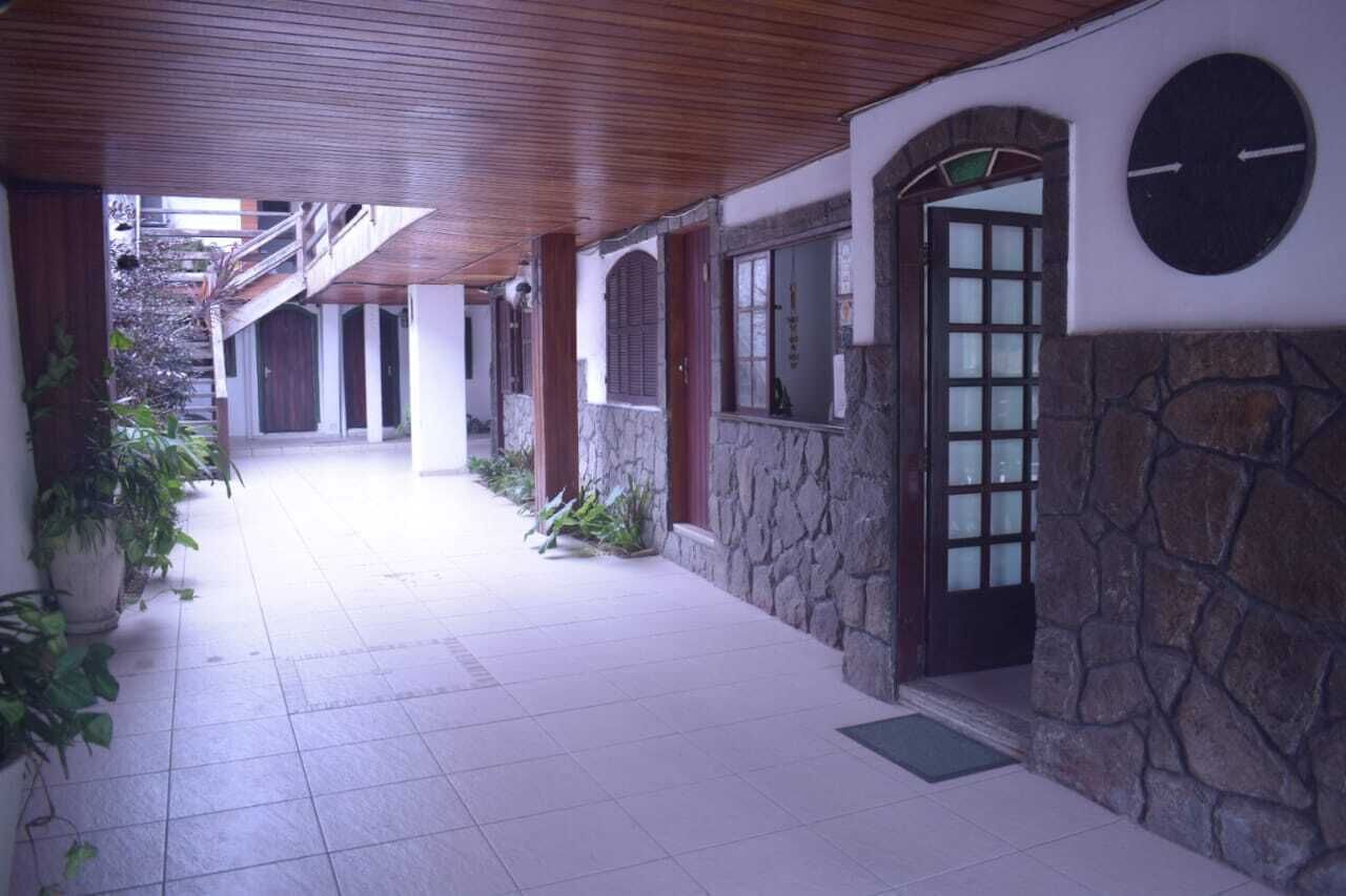 Un pasillo cubierto con paredes de piedra, puertas de madera y plantas en macetas.
