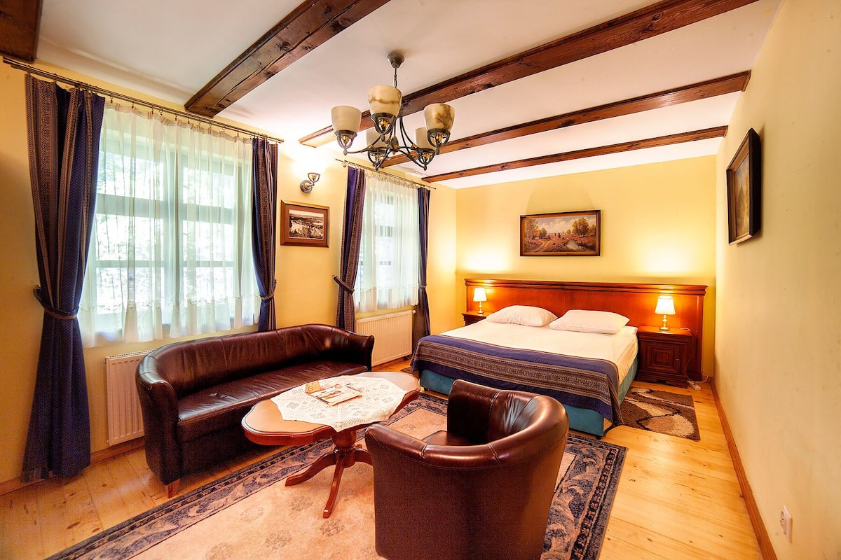 Une chambre à coucher avec un lit, un canapé, une petite table et un lustre.