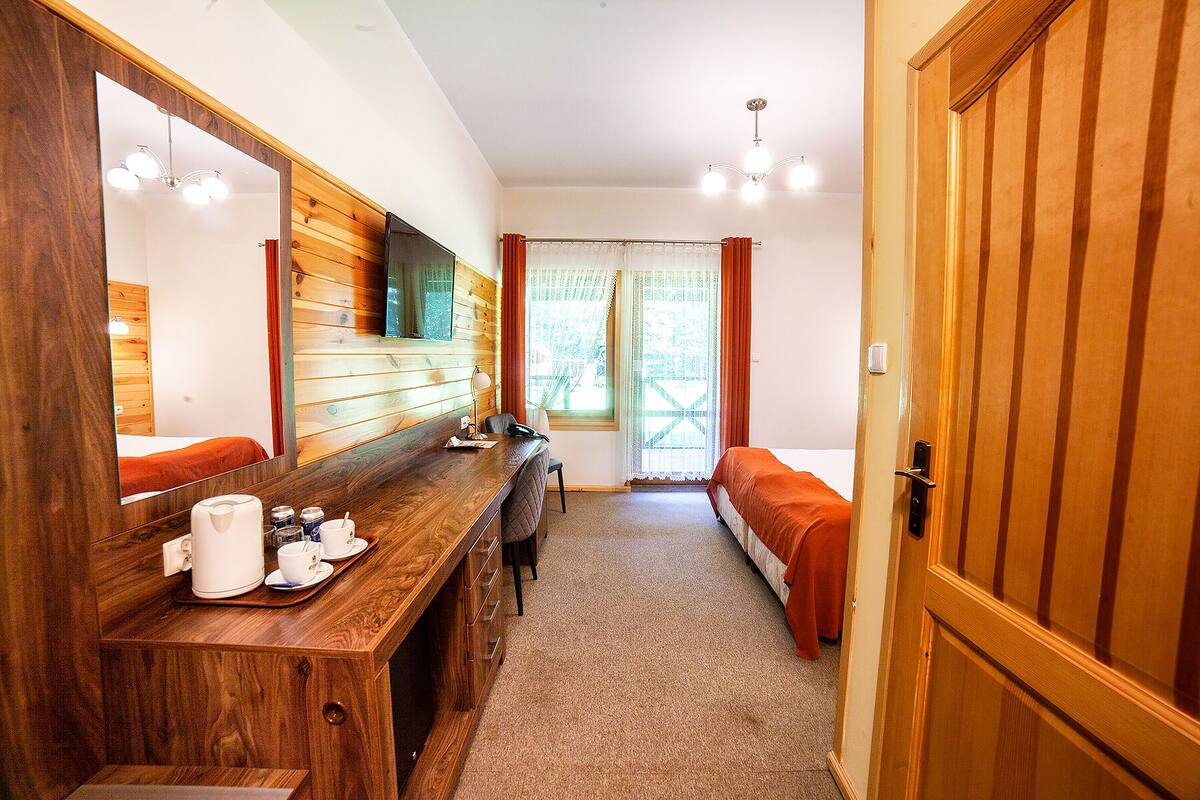 Une pièce confortable avec un bureau en bois, un lit, un banc et une porte.