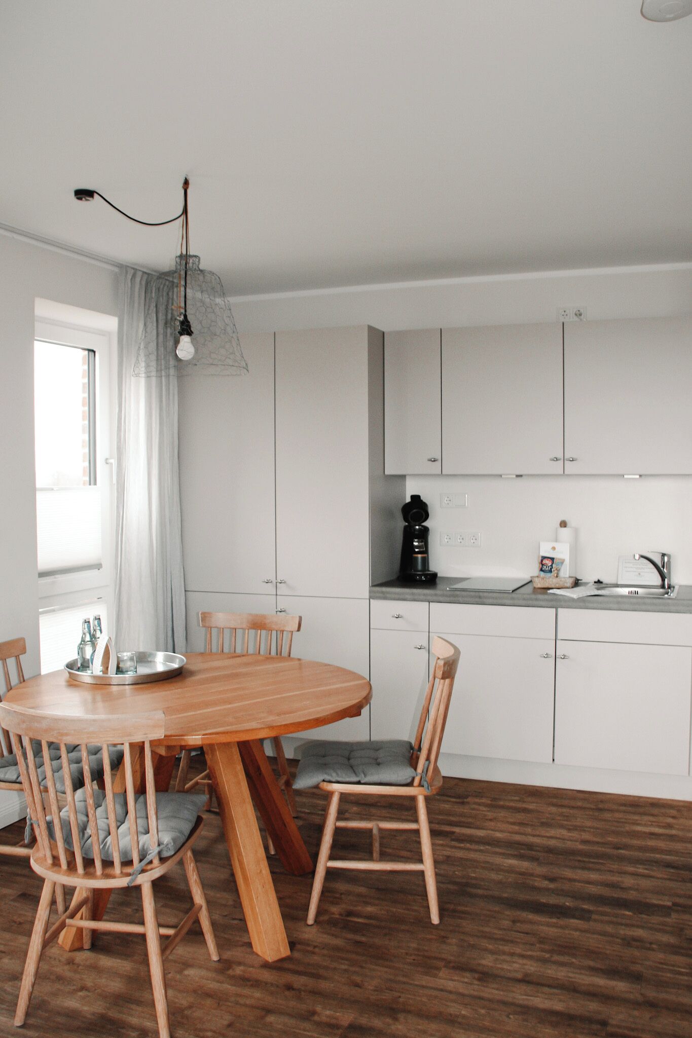 Una cocina moderna con armarios blancos, una mesa de comedor de madera y sillas.