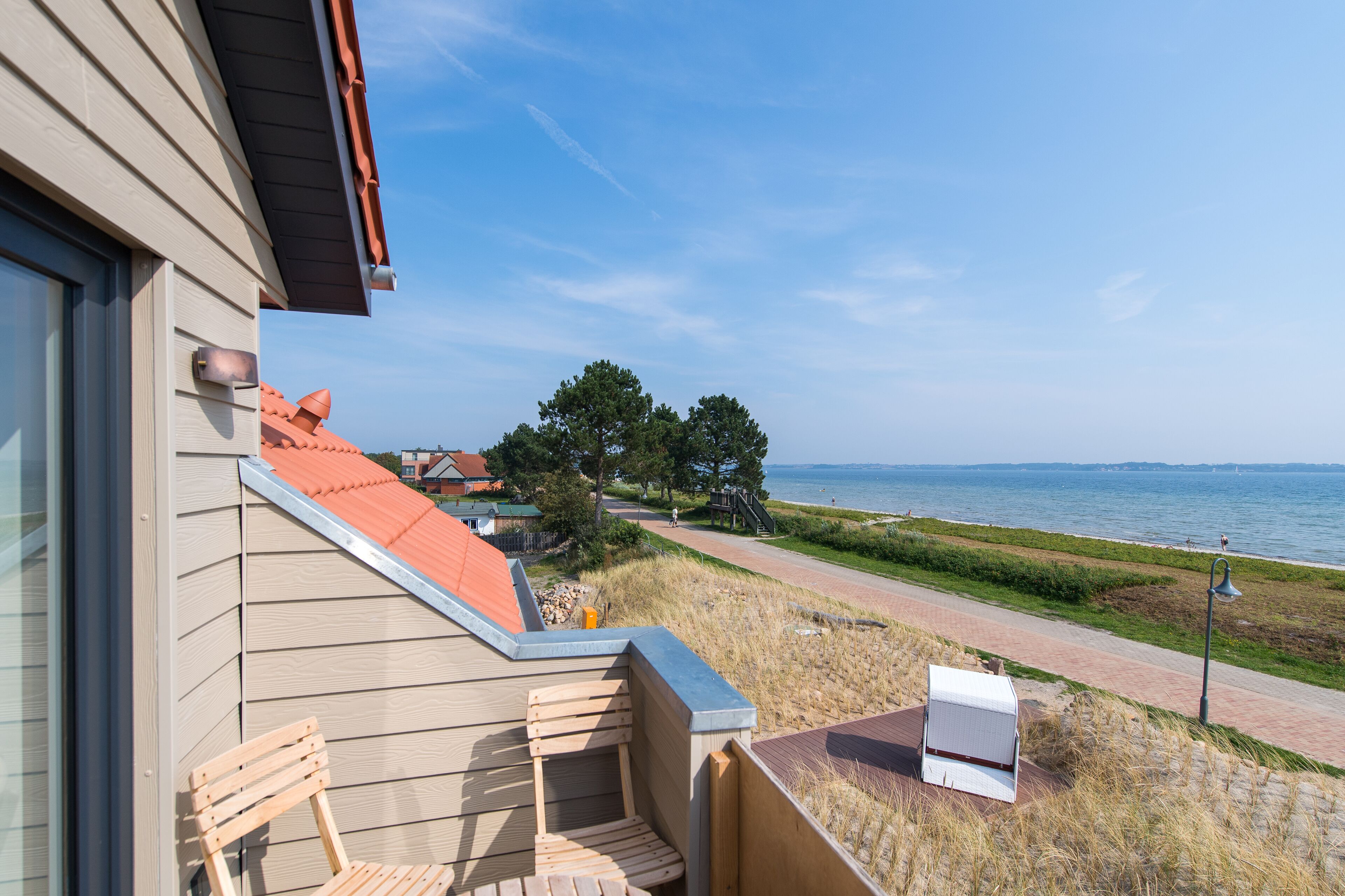 Un balcón con vistas al mar, una silla de madera y una pequeña mesa.