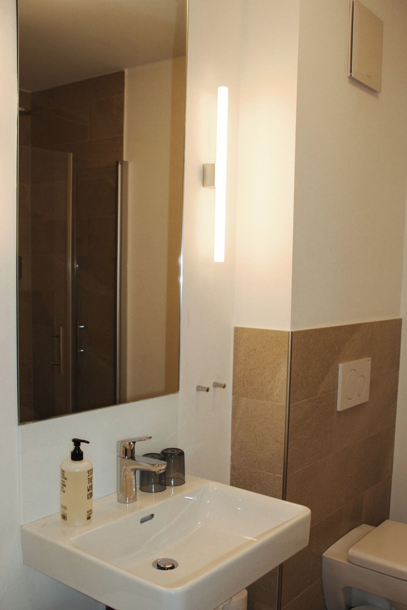 A bathroom with a white sink, a mirror, a shower, and a toilet.