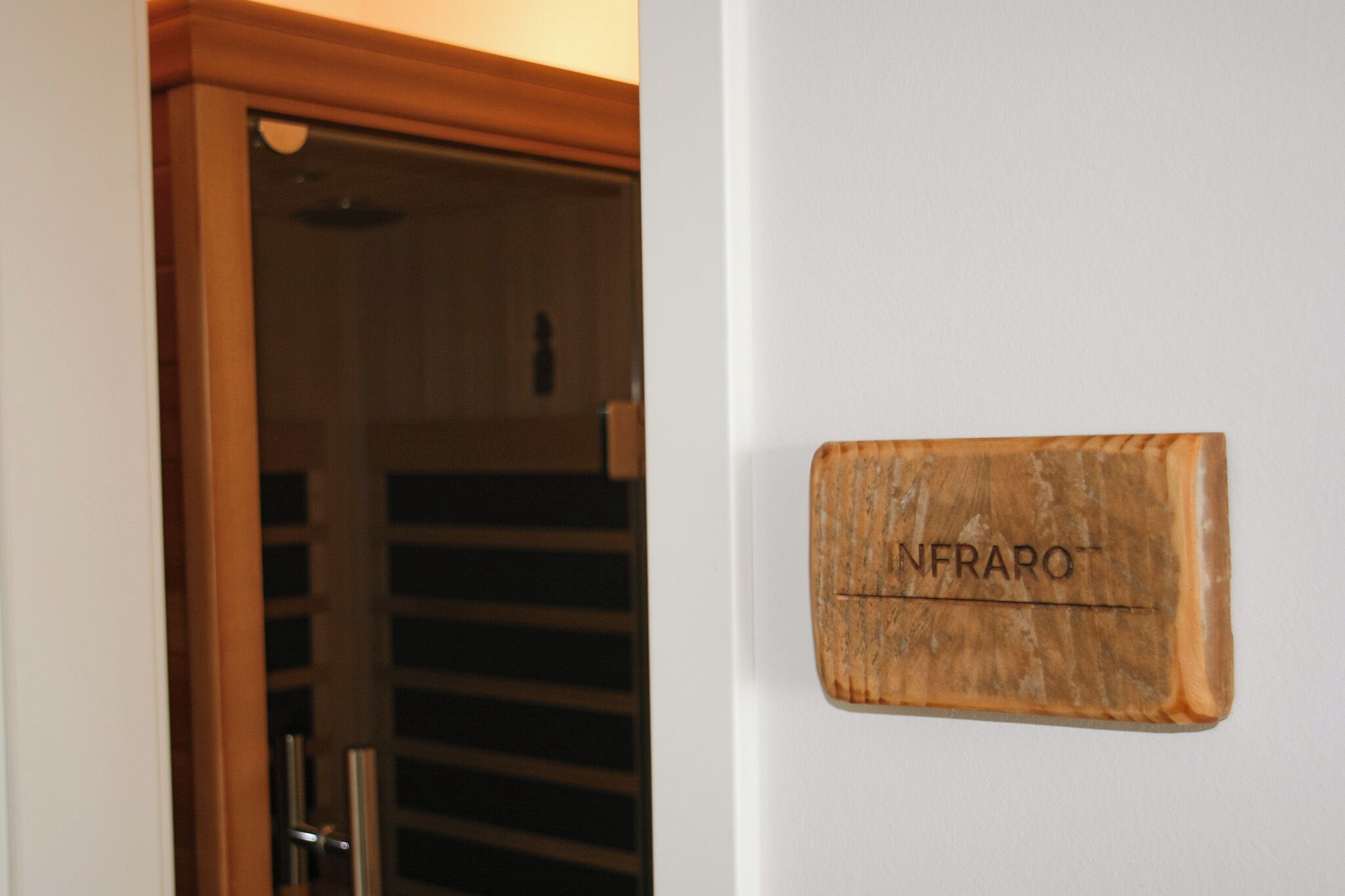 Una placa de madera con la inscripción 'INFRARO' sobre una pared blanca.