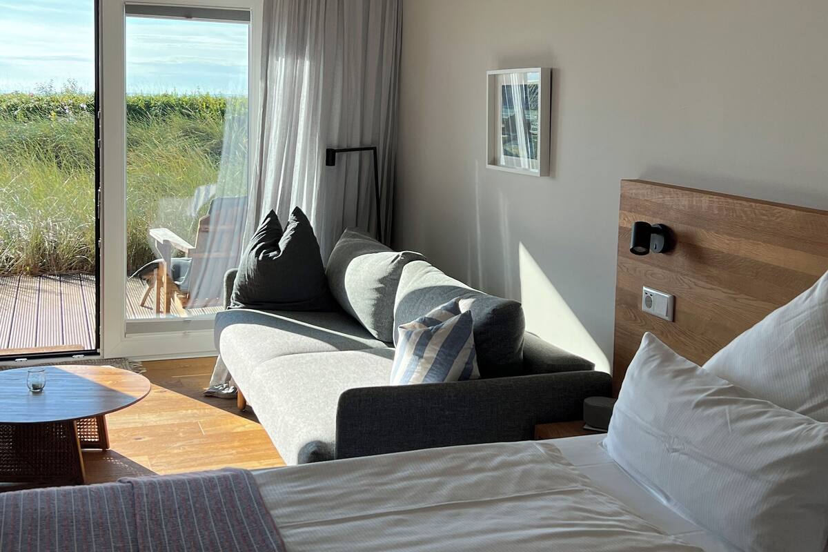Een hotelkamer met een bed, een bank, een klein tafeltje en uitzicht op de omgeving.