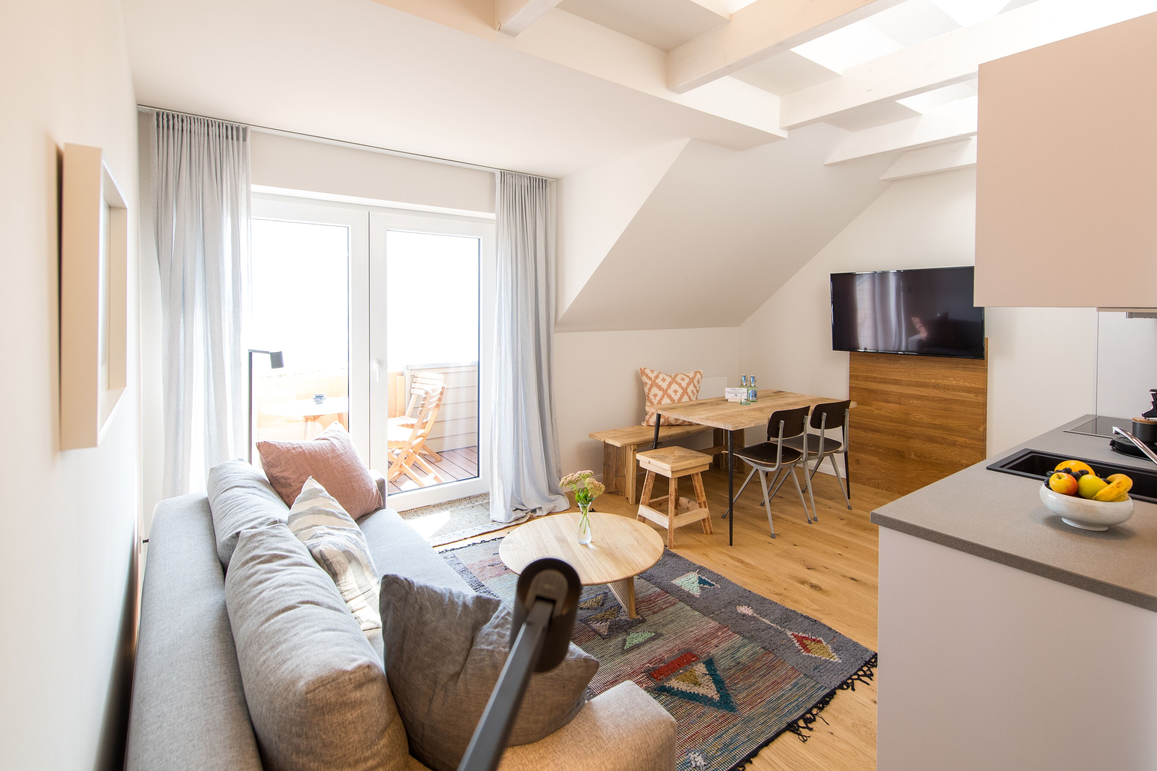 Una sala de estar moderna con un sofá, una mesa de comedor y una zona de cocina con televisión.