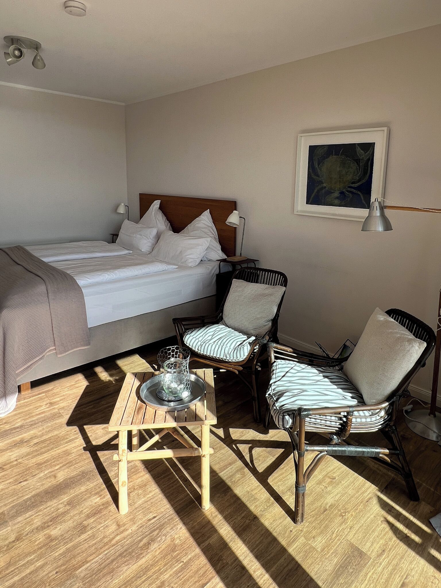 Une chambre à coucher avec un lit, deux chaises, une petite table et une lampe.
