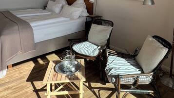 A bedroom with a bed, two chairs, a small table, and a lamp.