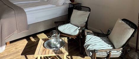 Une chambre à coucher avec un lit, deux chaises, une petite table et une lampe.