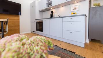 A modern kitchen with white cabinetry, a built-in oven, and a coffee machine.
