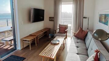Una sala de estar con sofá, mesa de centro de madera, televisor y una silla.