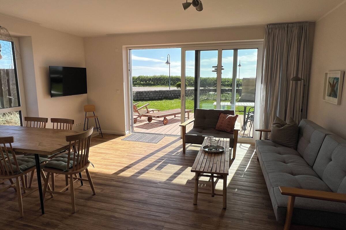 Een ruime woonkamer met een eettafel, stoelen, een bank en een televisie.