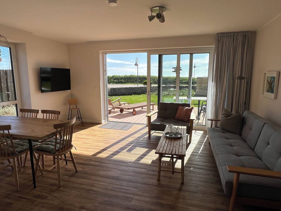 A spacious living area with a dining table, chairs, a sofa, and a television.