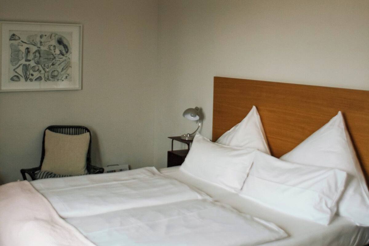 Een hotelkamer met een bed, een stoel, een nachtkastje en een plafondlamp.