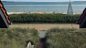 Un camino que lleva a una playa, con vista despejada al mar y un faro en la distancia.
