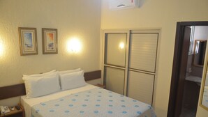 A hotel room with a bed, a nightstand with a phone, two framed pictures on the wall, and a sliding door closet. - Pousada Porto Canal (Cabo Frio)