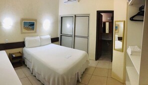 A hotel room with a bed, bedside table, and a wardrobe. - Pousada Porto Canal (Cabo Frio)