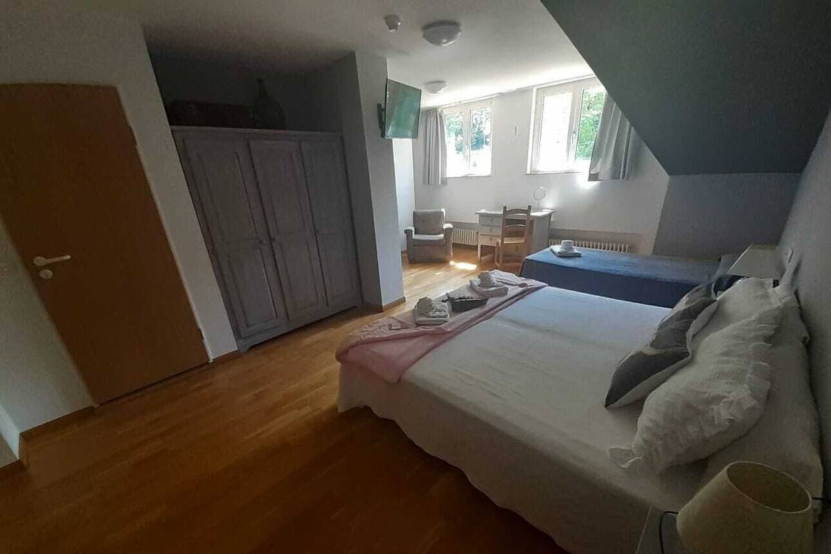 A bedroom with a bed, bedside table, and a view of a dining area.