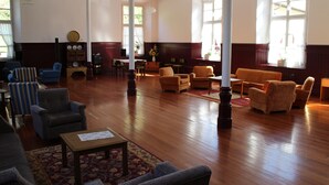 A spacious room with wooden flooring, multiple seating areas including armchairs and sofas, a coffee table, and large windows providing natural light. - Balneario Casa Pallotti (Valle de Carranza)