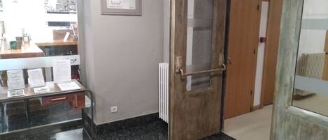 Een kamer met een houten deur, een radiator en een toonbank met papieren.