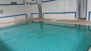 Piscina com paredes azulejadas e fundo azul transparente.