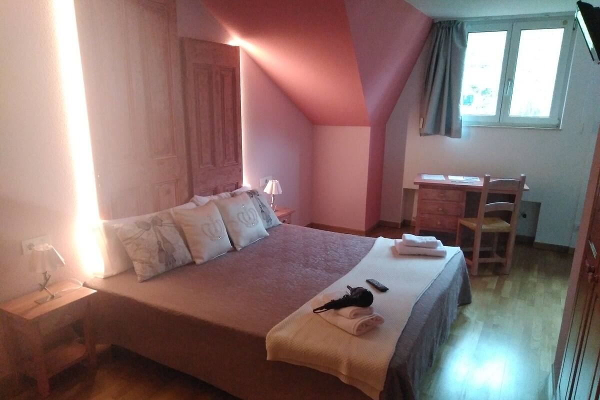 A bedroom with a bed, a desk, a chair, and a window.