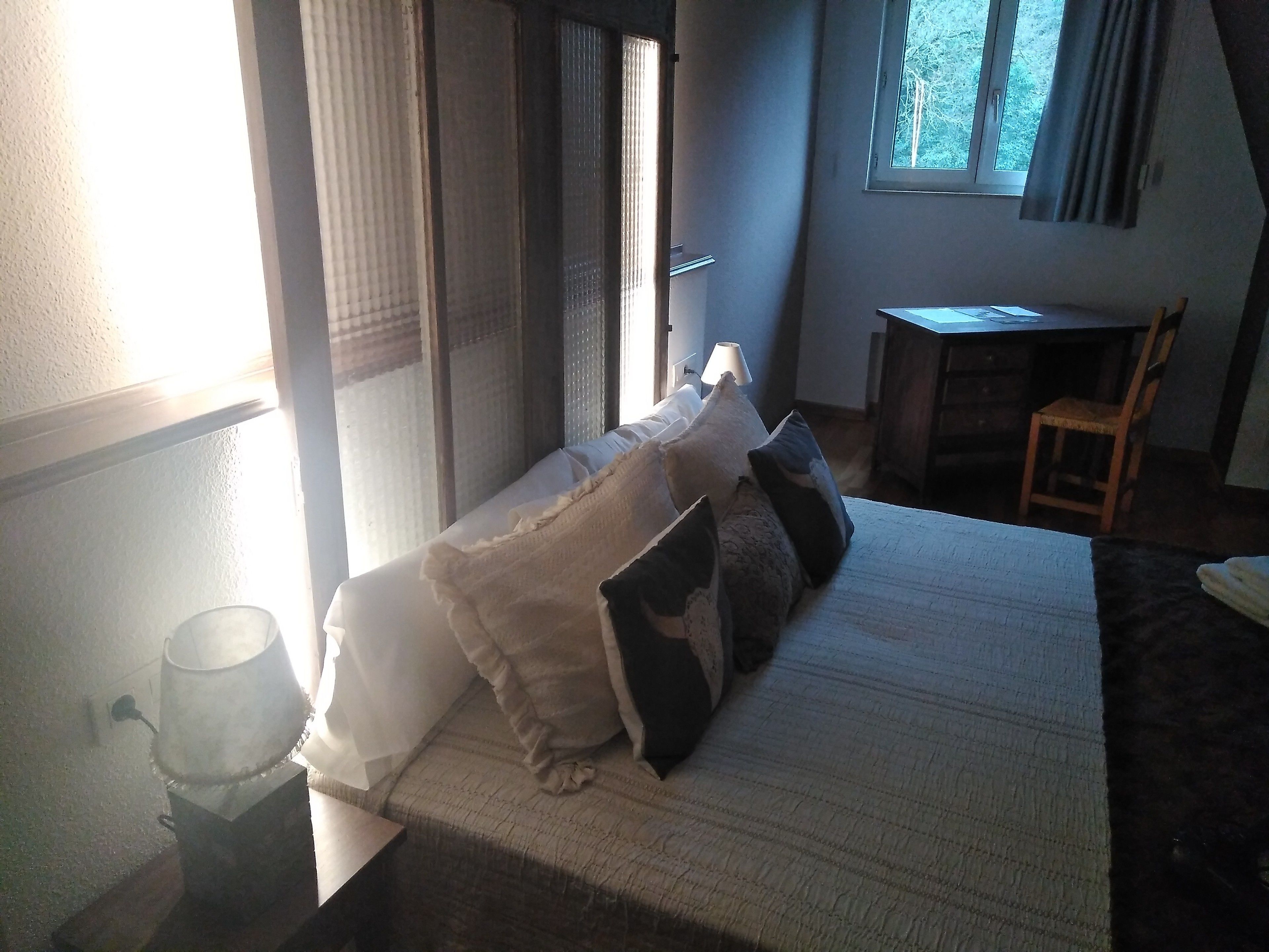 A bedroom with a bed, a desk, and a chair.