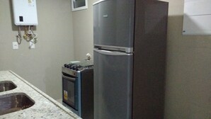 Una cocina con un refrigerador de acero inoxidable, una estufa a gas y un horno empotrado.