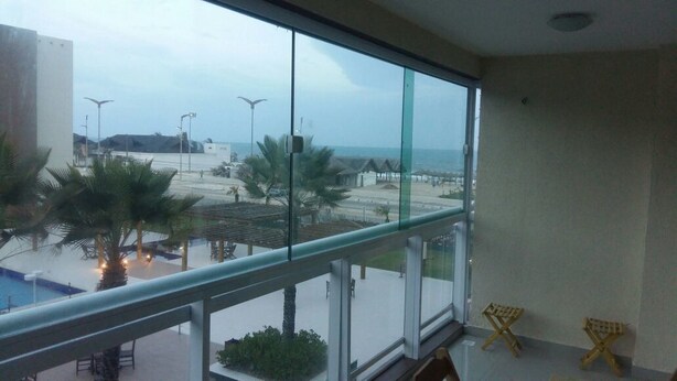 Un balcón con vista a la playa y la piscina.