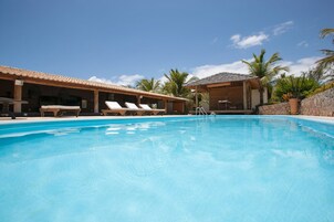 Una piscina al aire libre, sillones reclinables de piscina