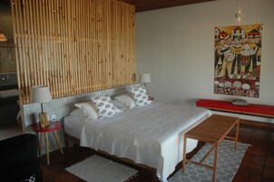 Un dormitorio con cama, mesitas de noche, un banco y un panel de pared de madera.
