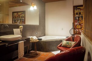 Un baño moderno con una bañera grande, un tocador con lavamanos y una silla de cuero rojo.