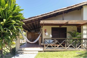 A building with a covered porch, a hammock, and a wooden fence.