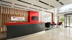 A modern reception area with a red counter, a mounted TV, and a seating area with red chairs. - Ramada Encore by Wyndham Gebze (Gebze)