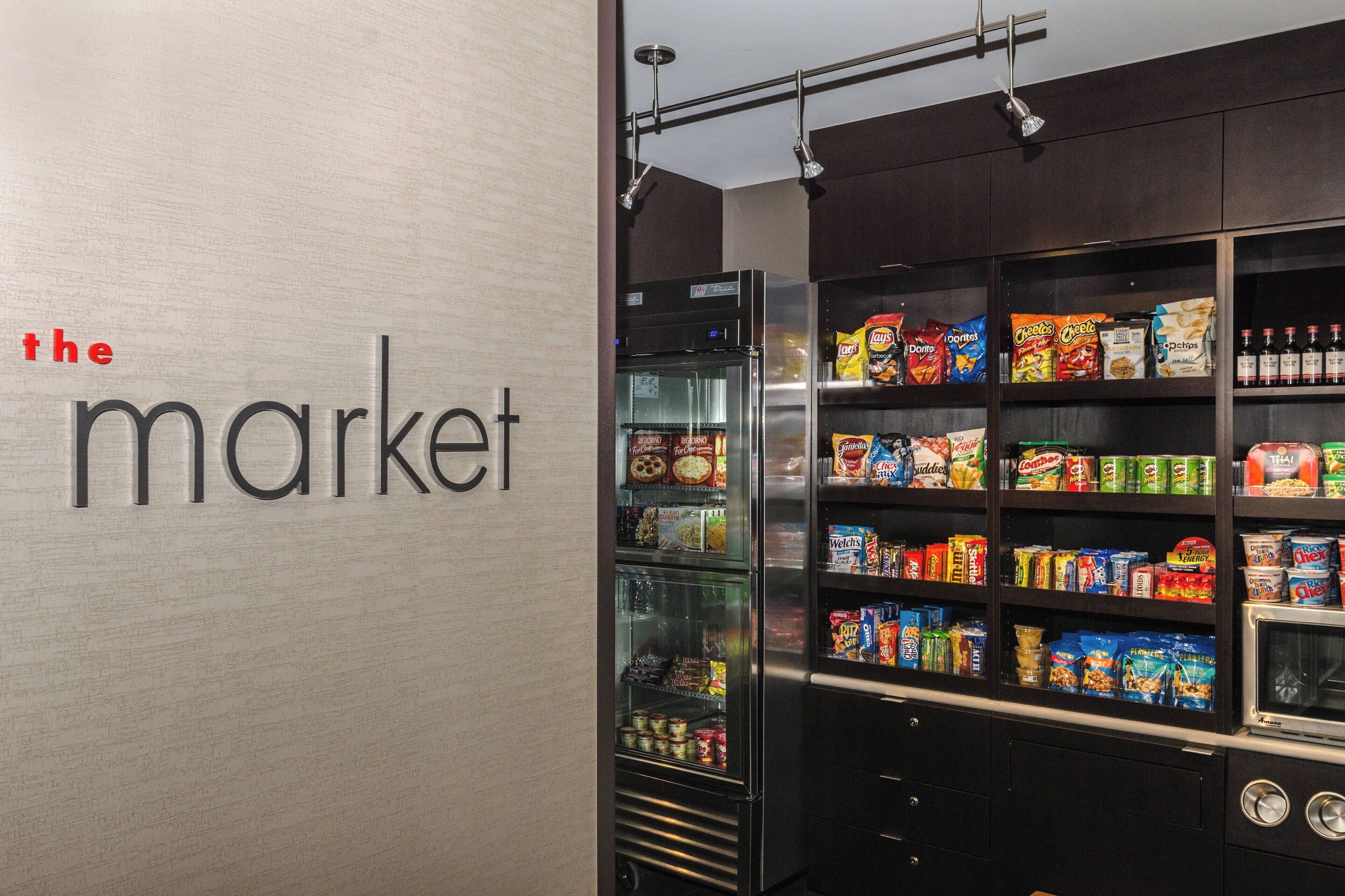 A snack display area with various packaged foods and a refrigerator.