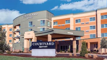 Un hotel Courtyard Marriott con diseño moderno, varios pisos y un cielo despejado.